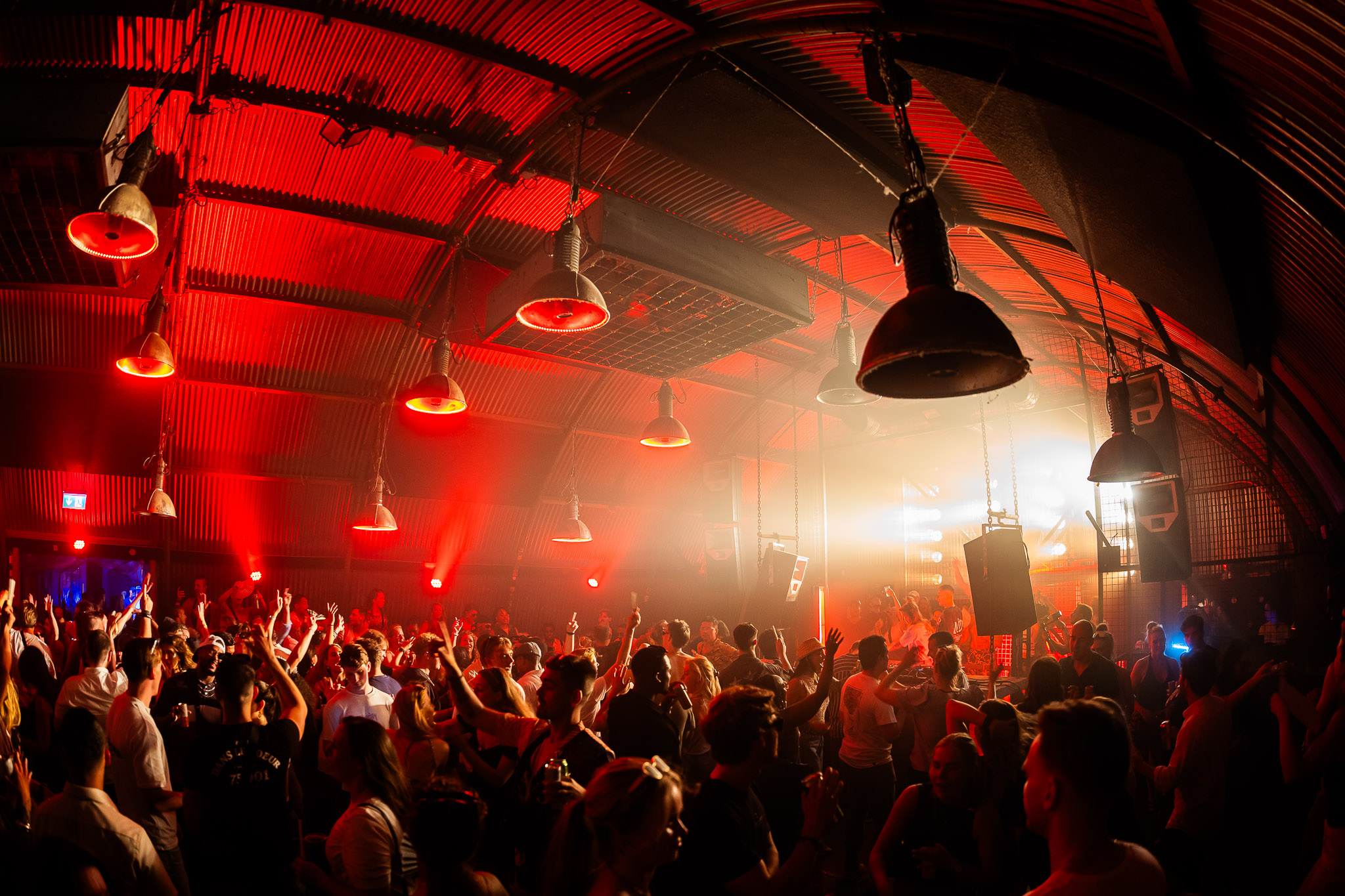 Red-lit hall with a full dancefloor